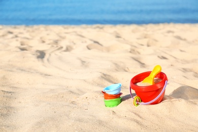 Photo of Set of plastic beach toys on sand near sea. Space for text