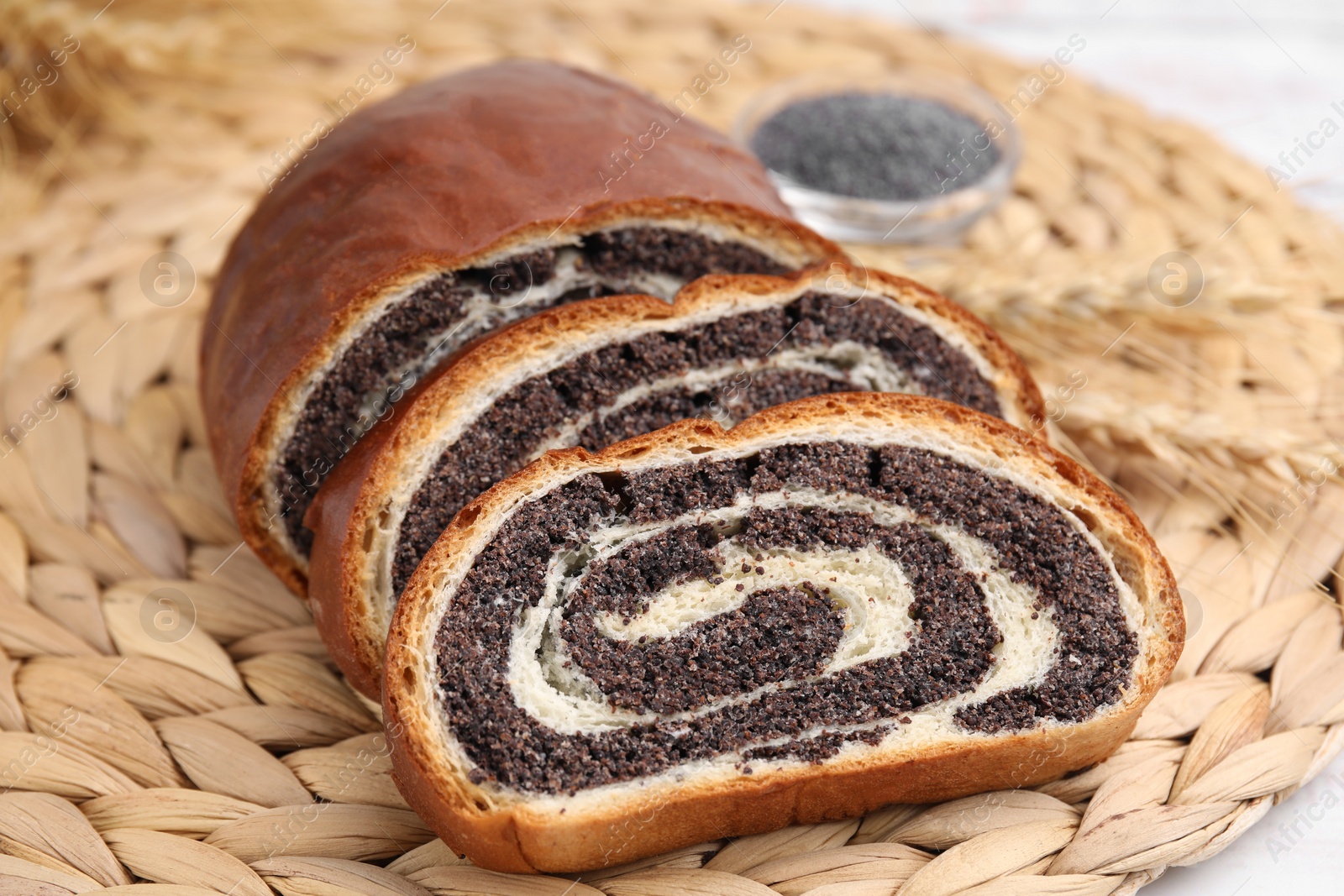 Photo of Cut poppy seed roll on wicker mat, closeup. Tasty cake