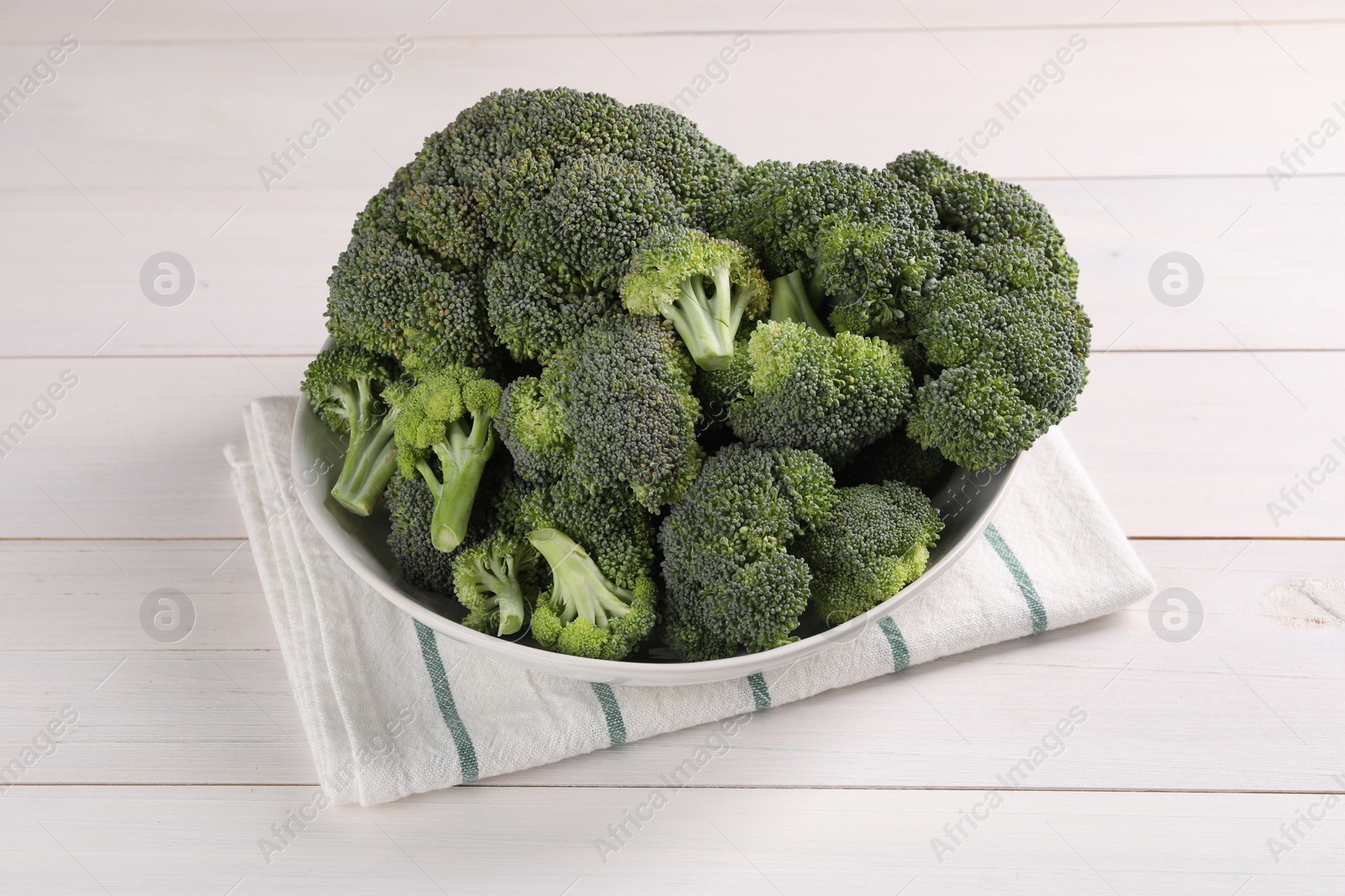 Photo of Bowl of fresh raw broccoli on white wooden table