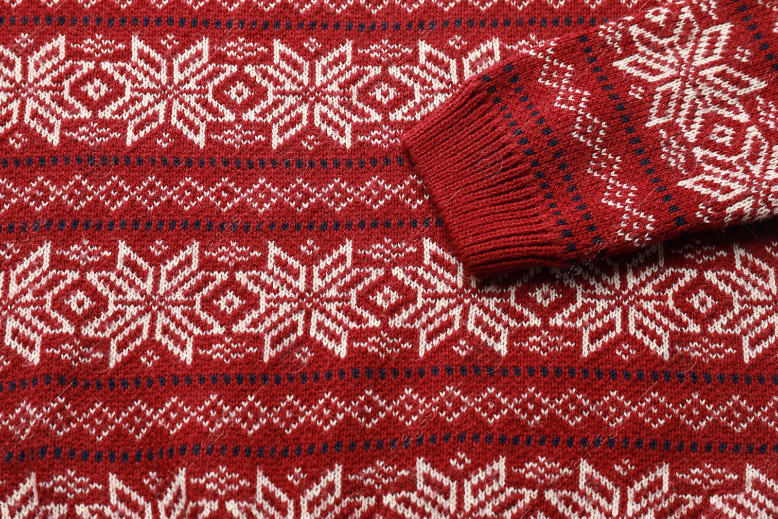 Photo of Warm Christmas sweater with snowflakes as background, closeup