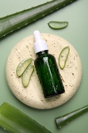 Photo of Flat lay composition with cosmetic products and cut aloe leaves on pale green background