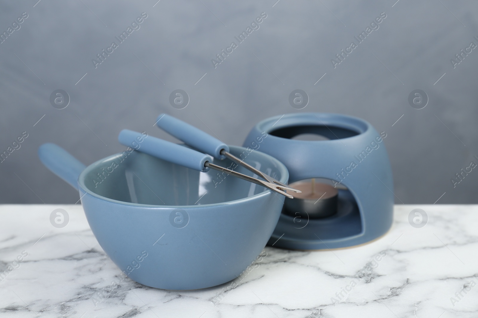 Photo of Fondue set on white marble table against light gray wall