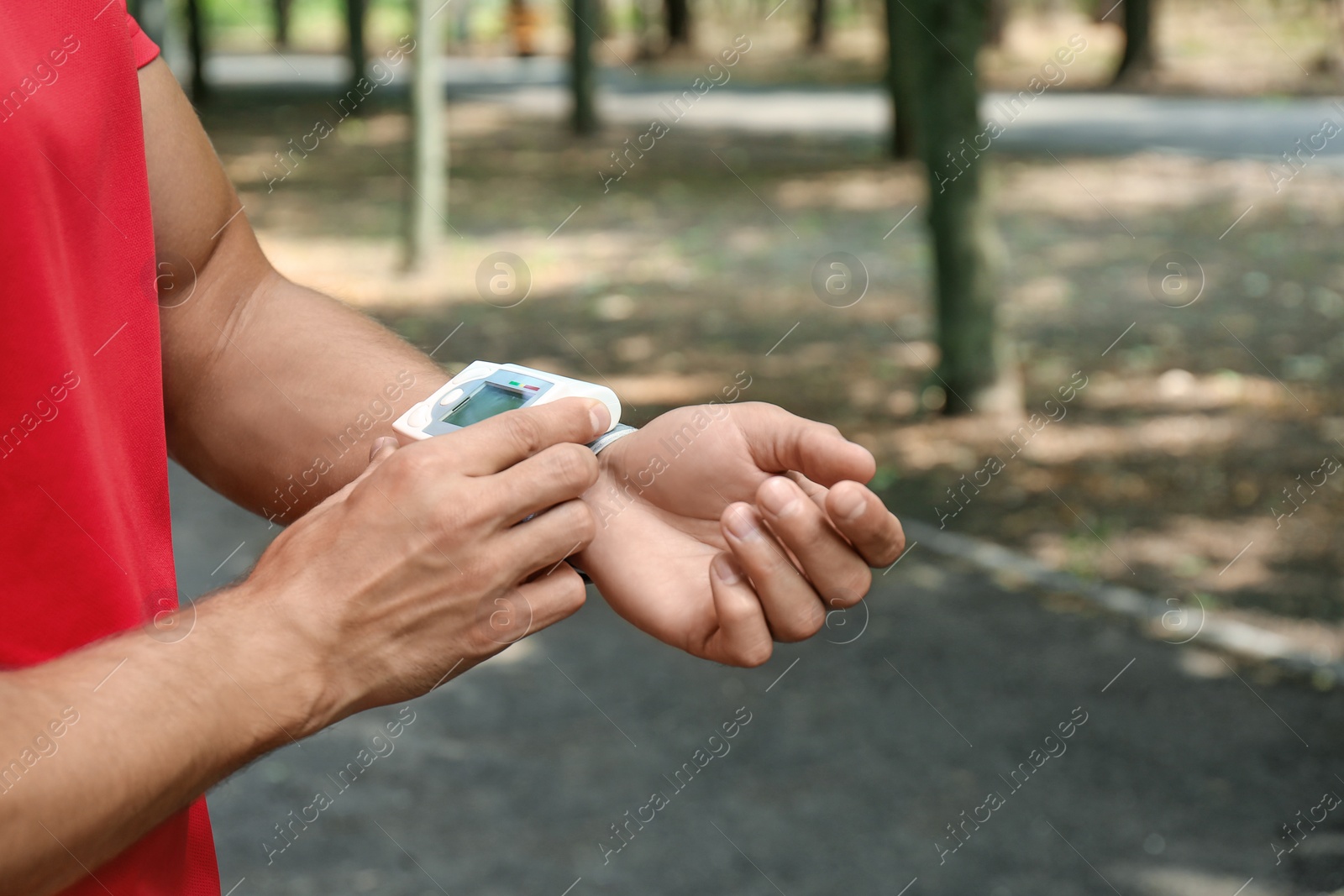 Photo of Young man checking pulse with medical device after training, closeup