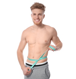 Portrait of young man with measuring tape showing his slim body on white background