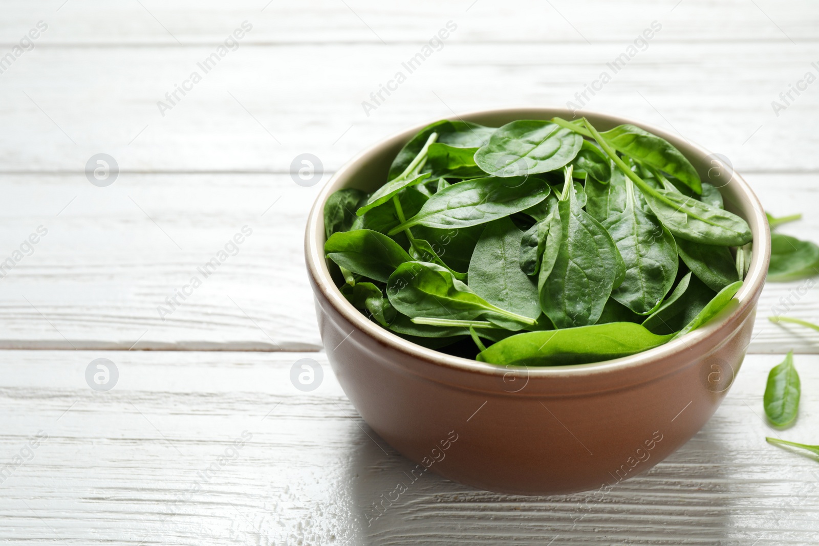 Photo of Fresh green healthy spinach on white wooden table. Space for text