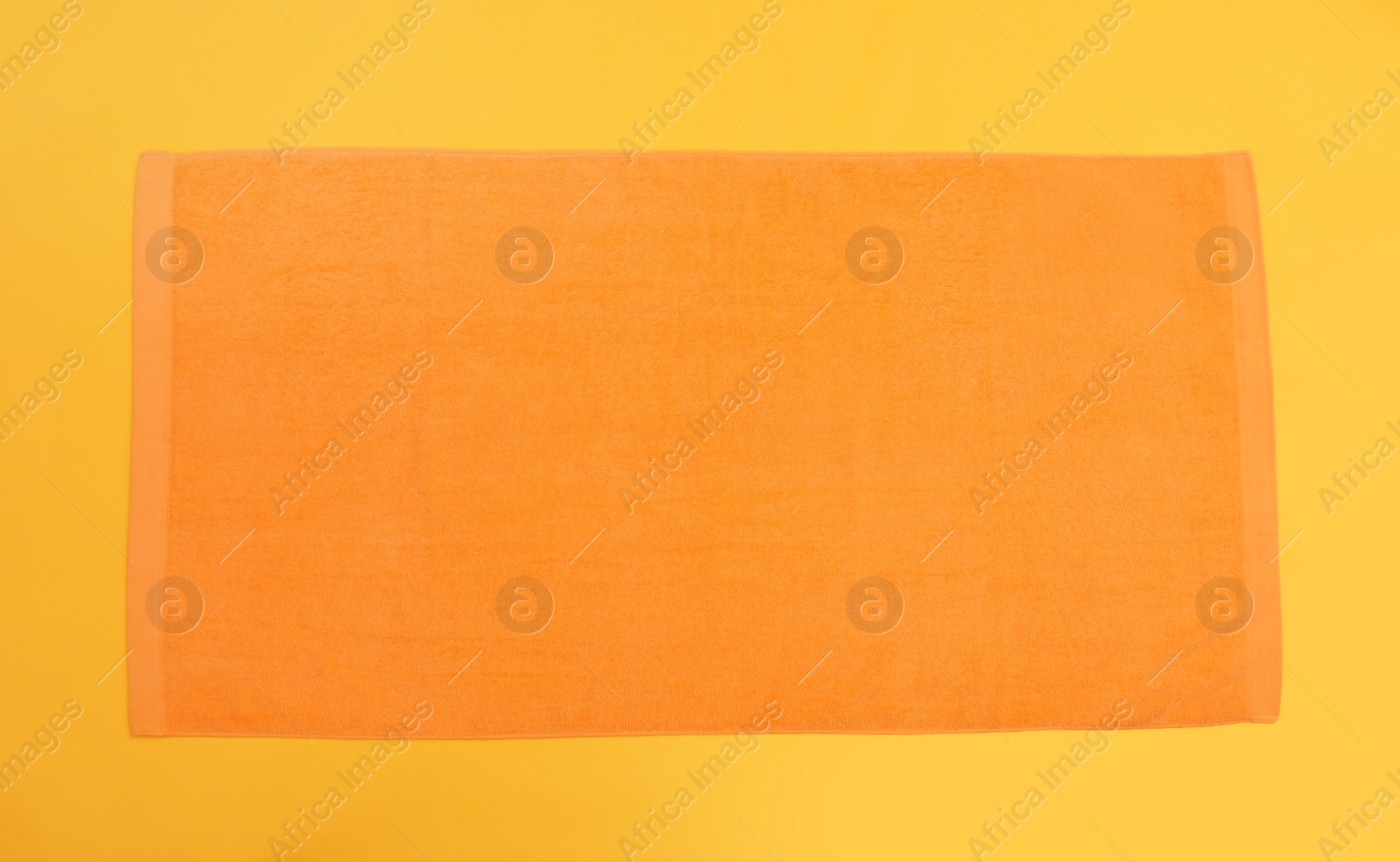 Photo of Orange beach towel on yellow background, top view