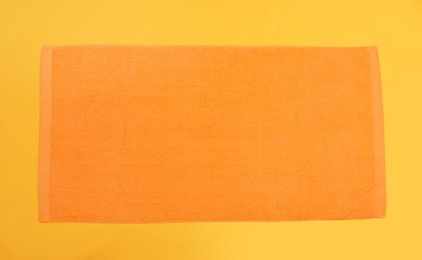 Orange beach towel on yellow background, top view