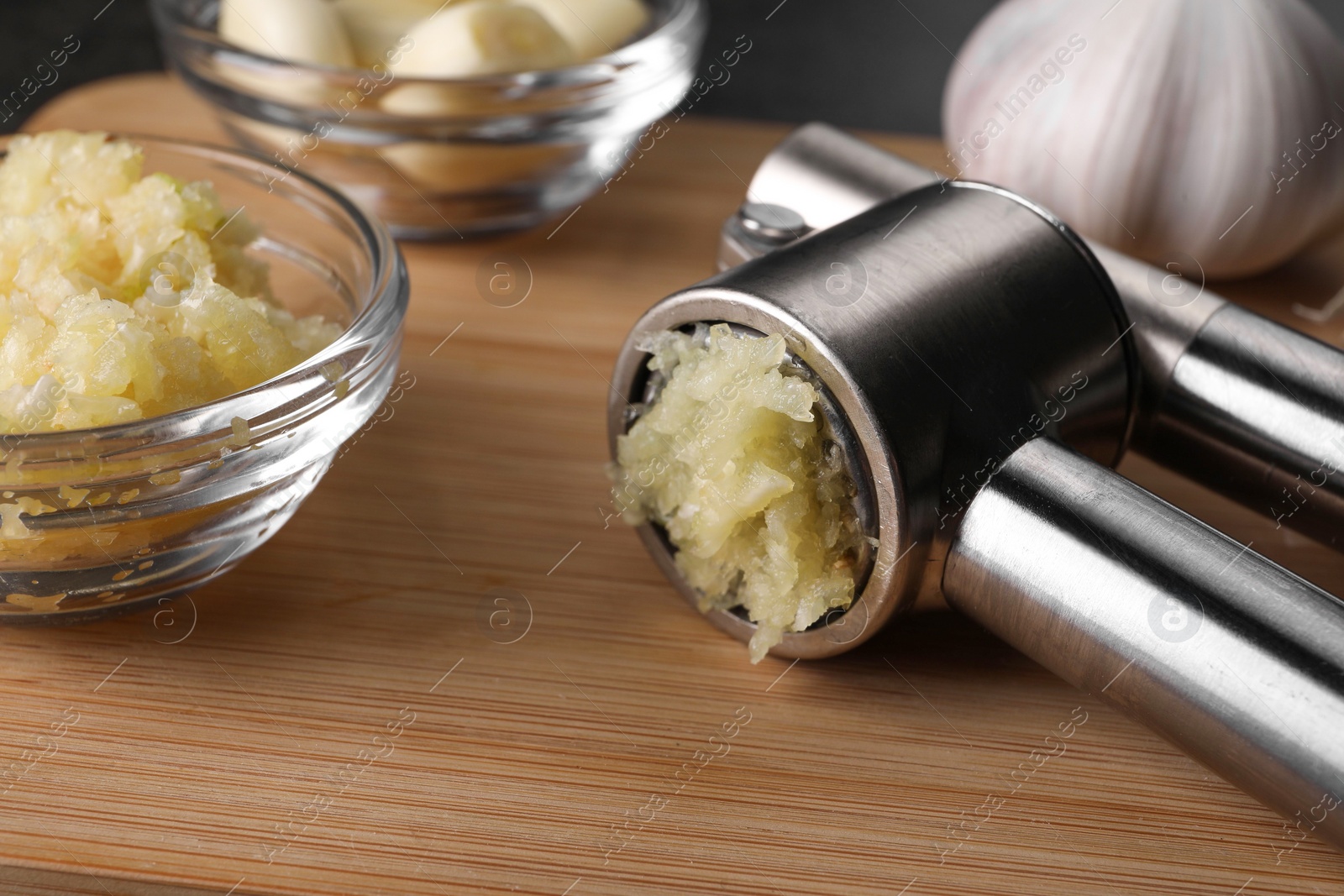 Photo of Garlic press and mince on wooden table, closeup