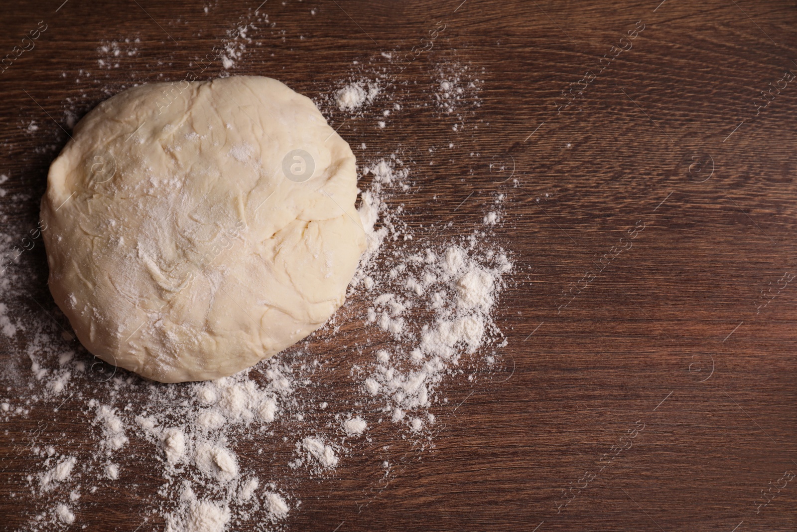 Photo of Fresh dough on wooden table, top view with space for text. Cooking grissini