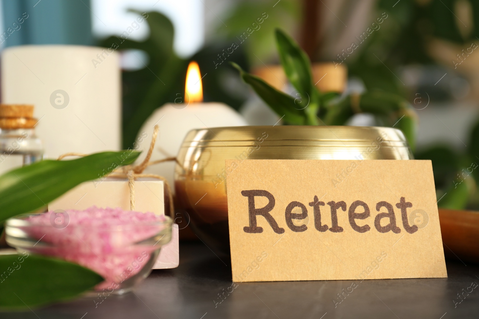 Photo of Retreat concept. Composition with card, singing bowl and different spa products on dark grey table, closeup