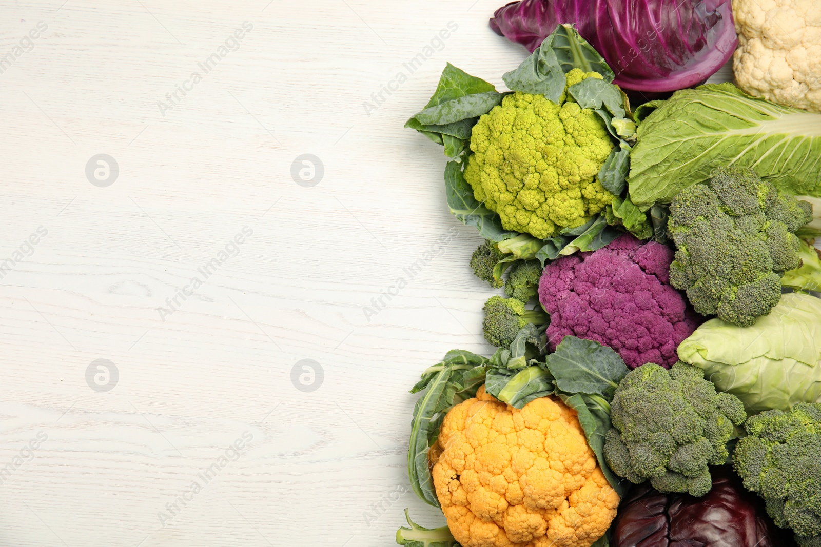 Photo of Different cabbages on wooden table, top view. Healthy food