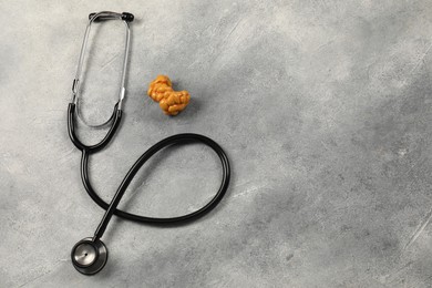 Photo of Endocrinology. Stethoscope and model of thyroid gland on grey table, top view. Space for text