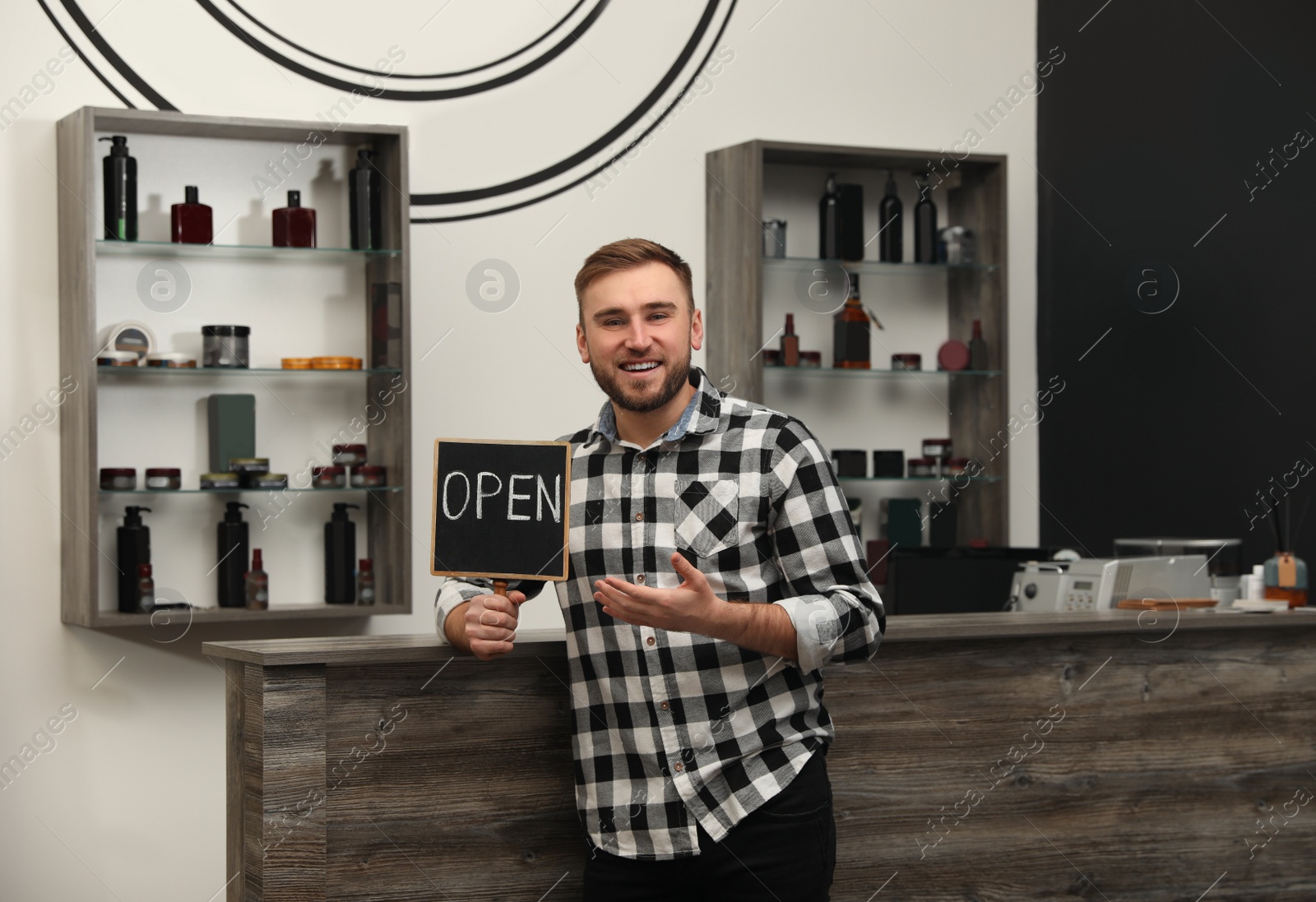 Photo of Young business owner holding OPEN sign in his barber shop