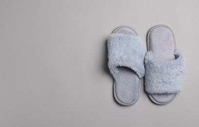 Photo of Pair of soft slippers on light grey background, top view. Space for text