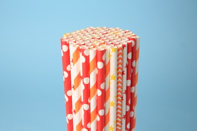 Colorful paper drinking straws on light blue background, closeup