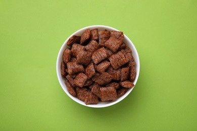 Chocolate cereal pads in bowl on green table, top view