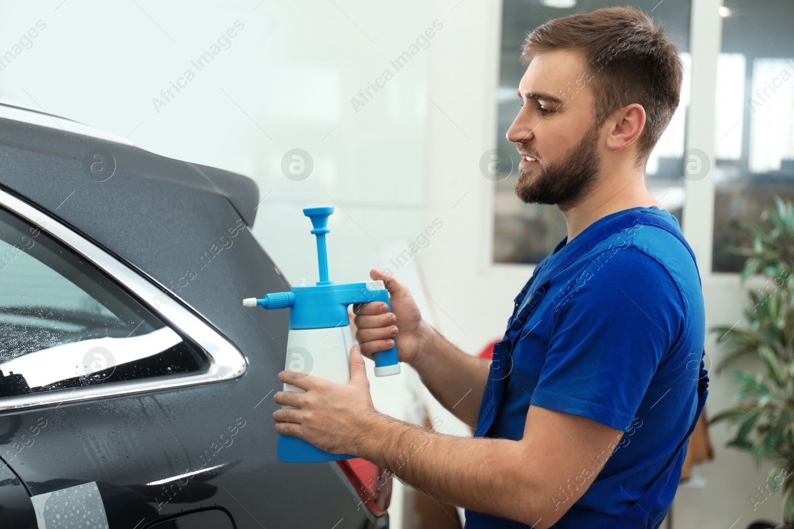 Photo of Worker spraying water onto car window before tinting