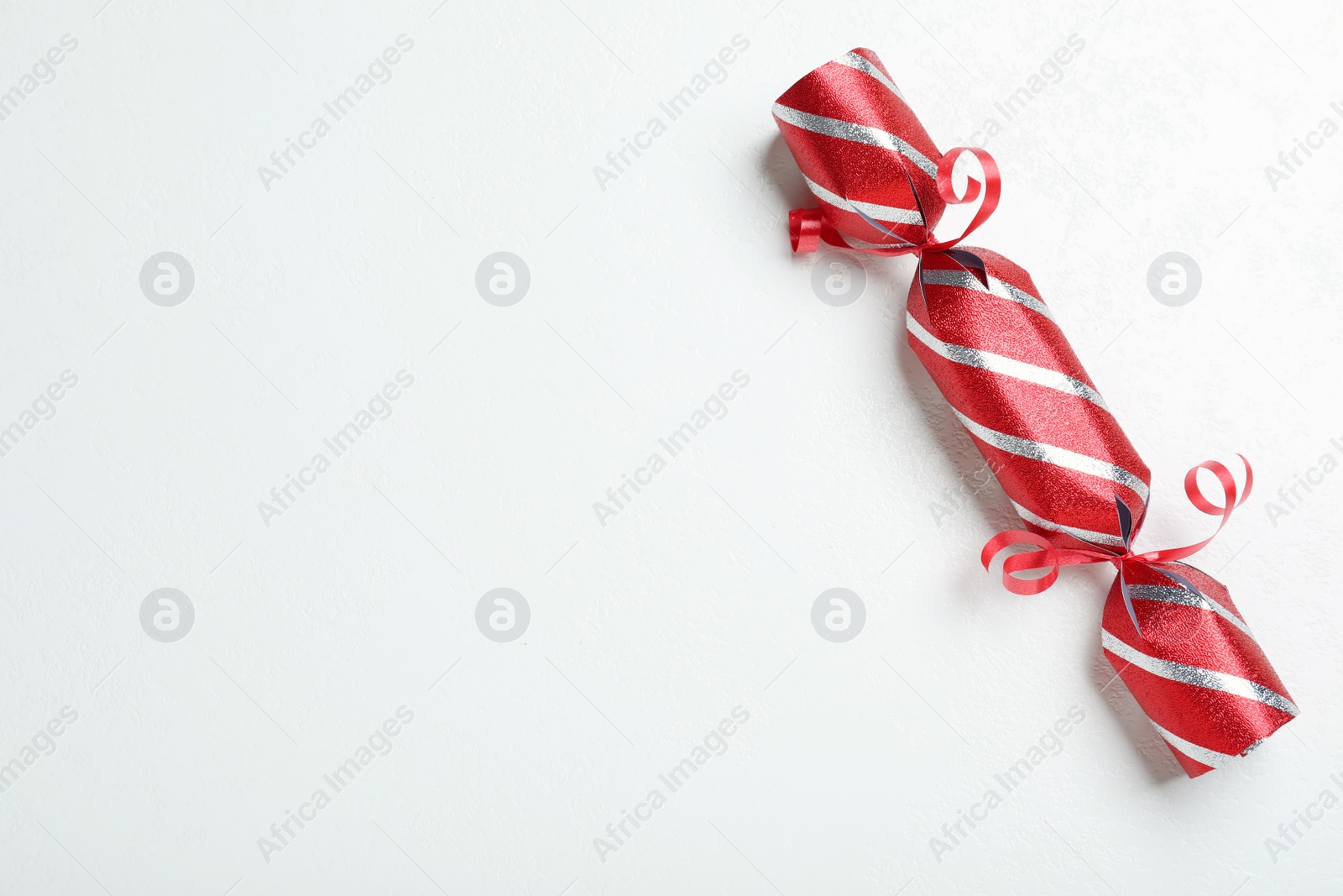 Photo of Red Christmas cracker on white background, top view. Space for text