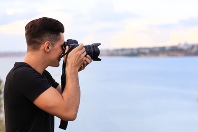 Photographer taking picture with professional camera near river