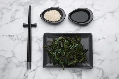 Fresh laminaria (kelp) seaweed served on white marble table, flat lay