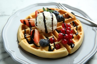 Photo of Delicious Belgian waffles with ice cream, berries and chocolate sauce on light marble table, closeup