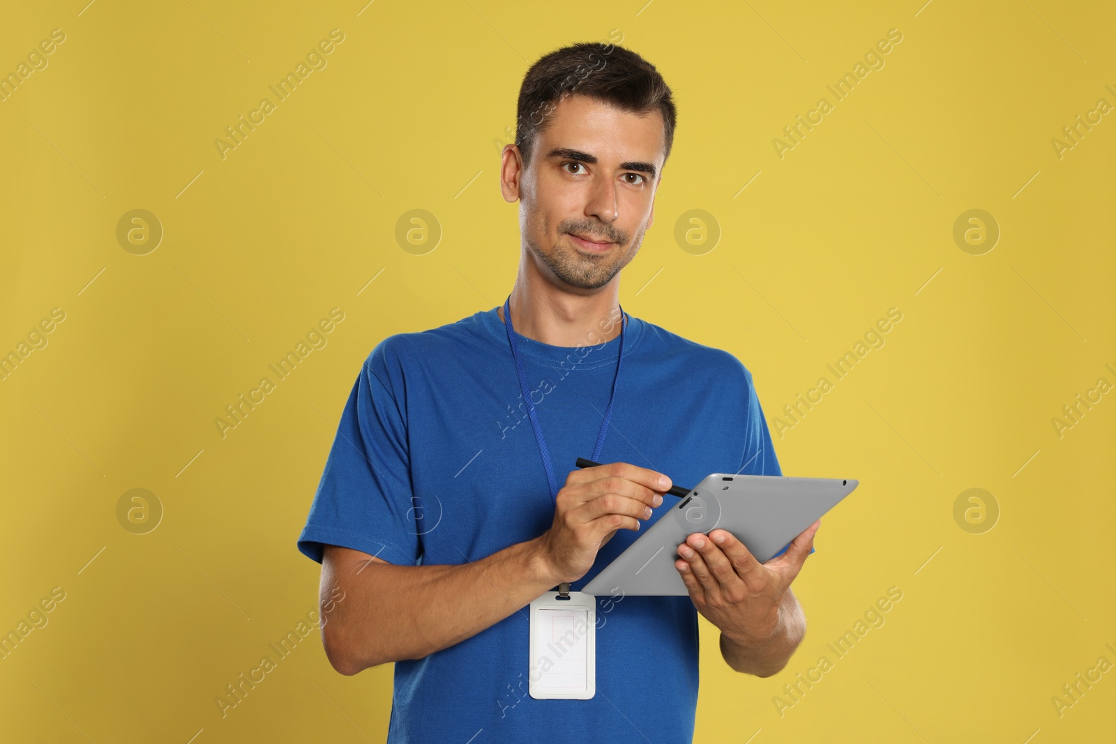 Photo of Happy young courier with tablet on yellow background