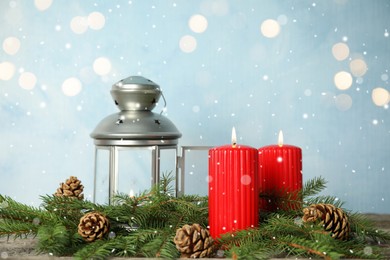 Photo of Snow falling on burning candles and Christmas lantern against blurred festive lights