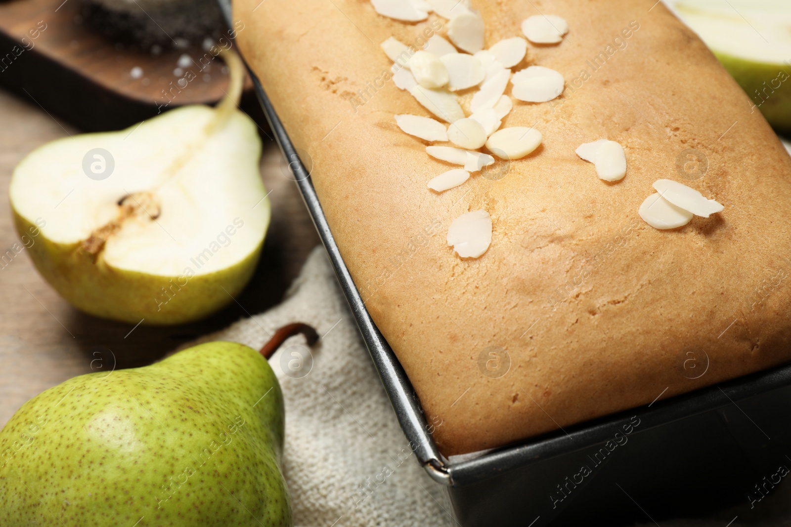 Photo of Tasty bread with almond flakes and pears on table, closeup. Homemade cake