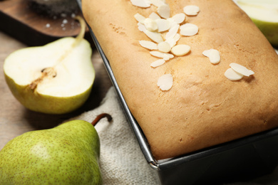 Tasty bread with almond flakes and pears on table, closeup. Homemade cake