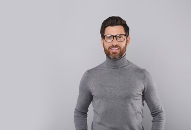 Portrait of handsome man in glasses on light grey background, space for text