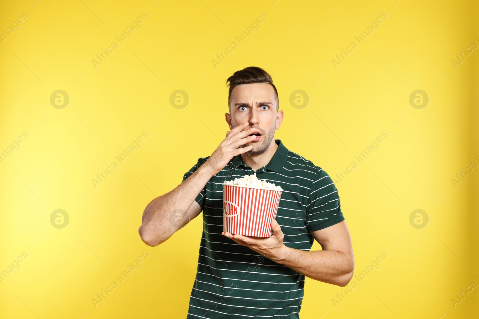 Photo of Emotional man with popcorn during cinema show on color background
