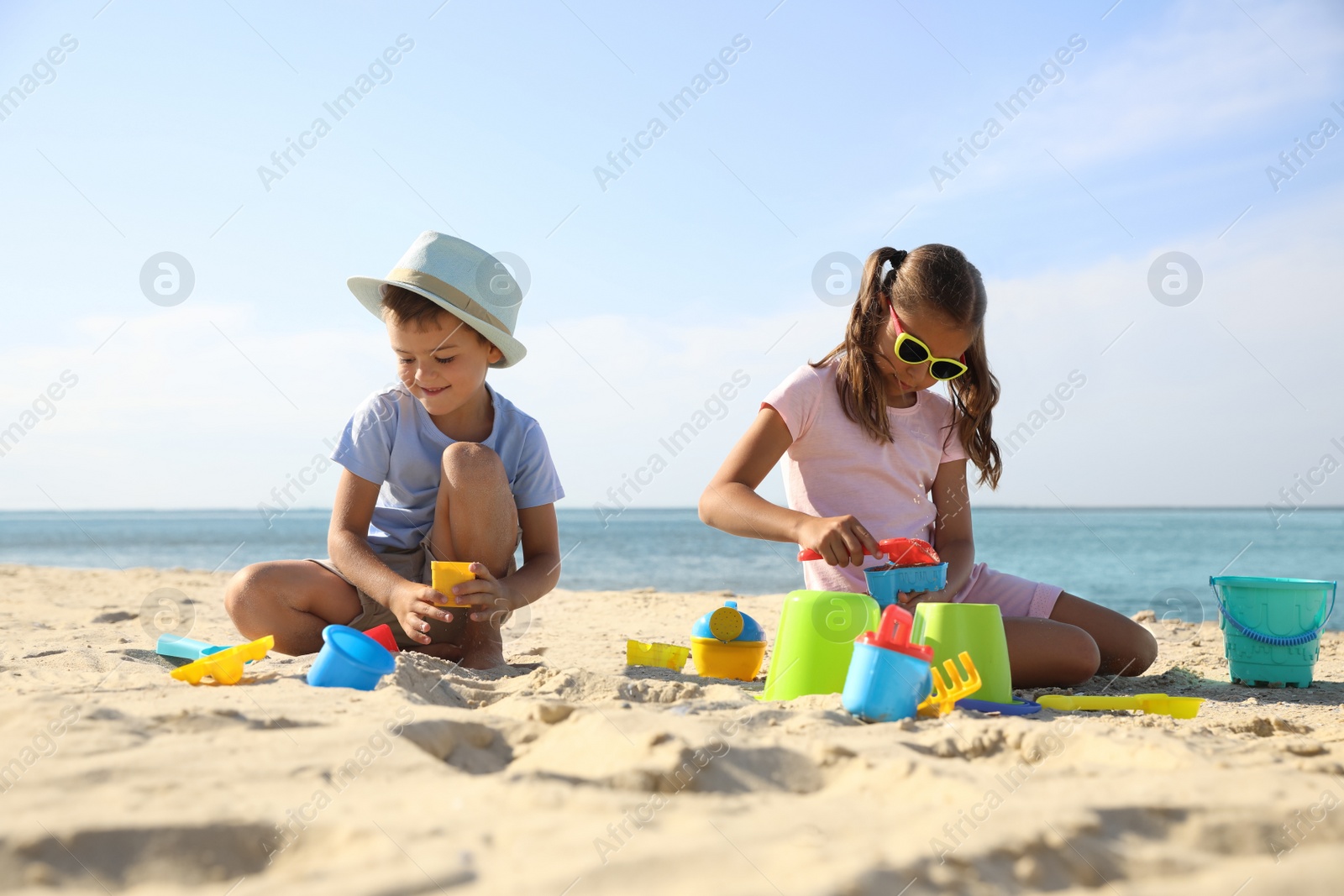 Photo of Cute little children playing with plastic toys on sandy beach