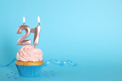 Photo of Delicious cupcake with number shaped candles on light blue background, space for text. Coming of age party - 21th birthday