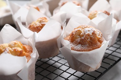 Photo of Delicious muffins with powdered sugar on light table, closeup