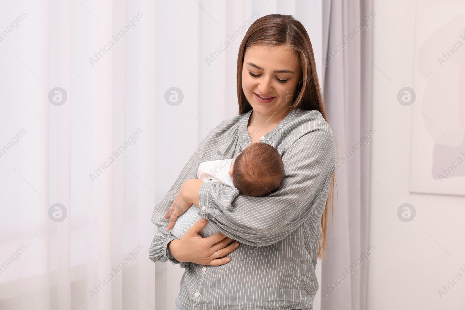 Photo of Happy mother with her cute newborn baby indoors. Space for text