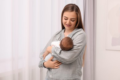 Photo of Happy mother with her cute newborn baby indoors. Space for text