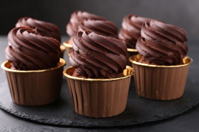 Photo of Delicious chocolate cupcakes on black textured table, closeup