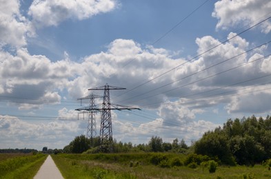 Modern high voltage towers in field on sunny day