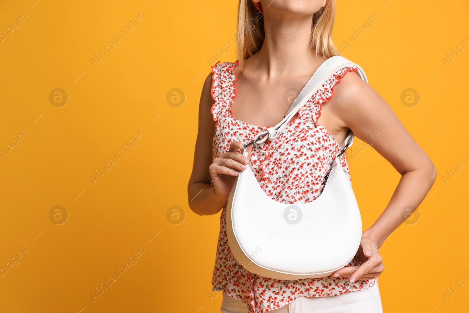 Photo of Stylish woman with trendy baguette bag on yellow background, closeup. Space for text