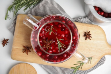 Photo of Tasty hot cranberry tea with rosemary and anise on white table, flat lay