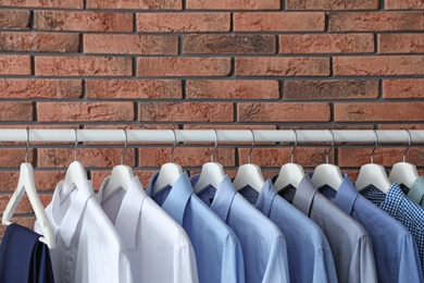 Photo of Wardrobe rack with men's clothes near brick wall