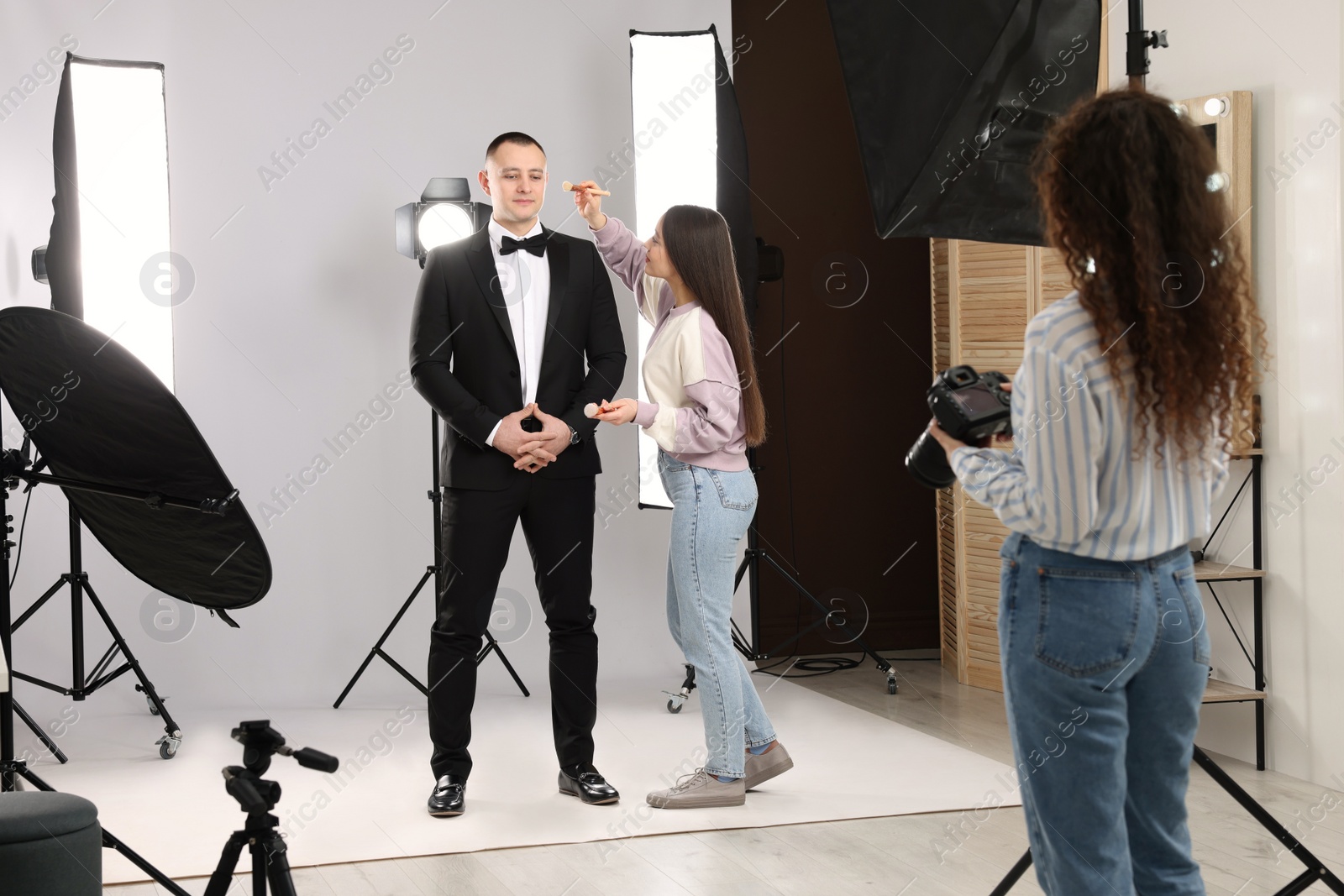 Photo of Professional photographer and makeup artist with model in studio