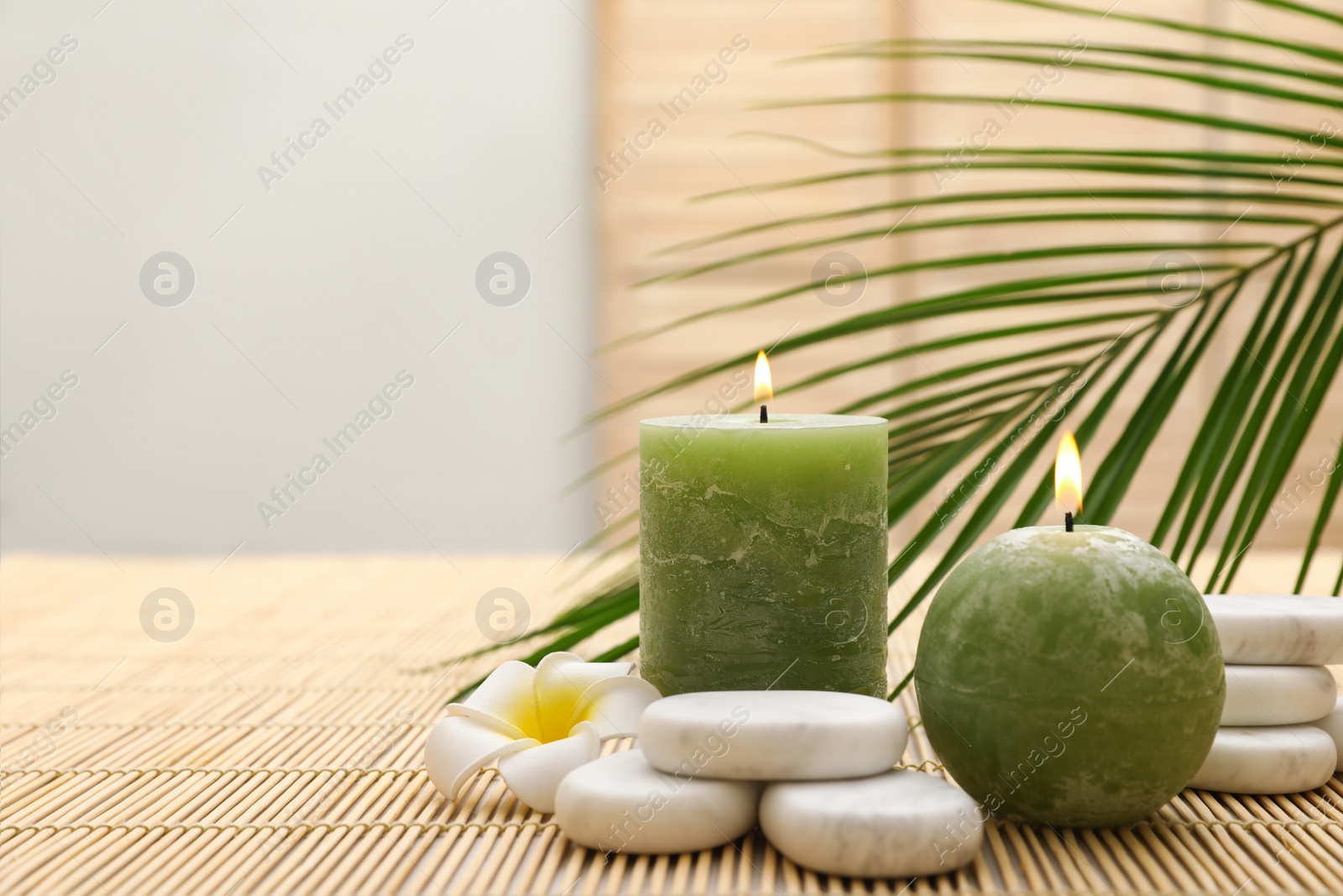 Photo of Composition with spa stones and candles on bamboo mat. Space for text