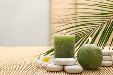 Composition with spa stones and candles on bamboo mat. Space for text