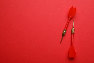 Plastic dart arrows on red background, flat lay with space for text