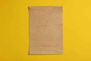 Photo of Sheet of old parchment paper on yellow background, top view