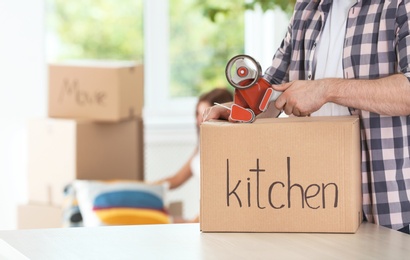 Man packing moving box indoors, closeup. Space for text