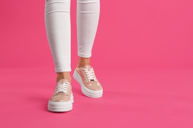 Woman wearing shoes on pink background, closeup. Space for text