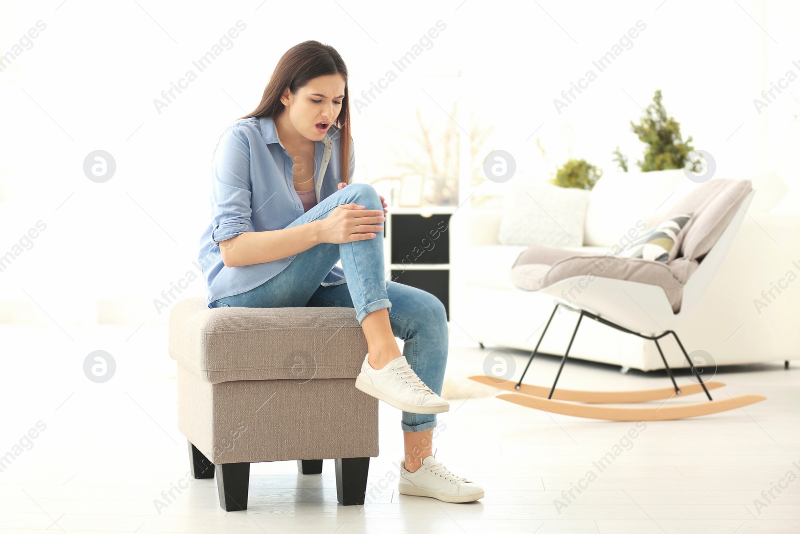 Photo of Young woman suffering from knee pain at home
