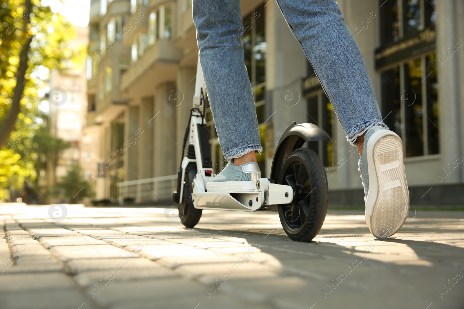 Photo of Woman riding electric kick scooter outdoors, closeup. Space for text